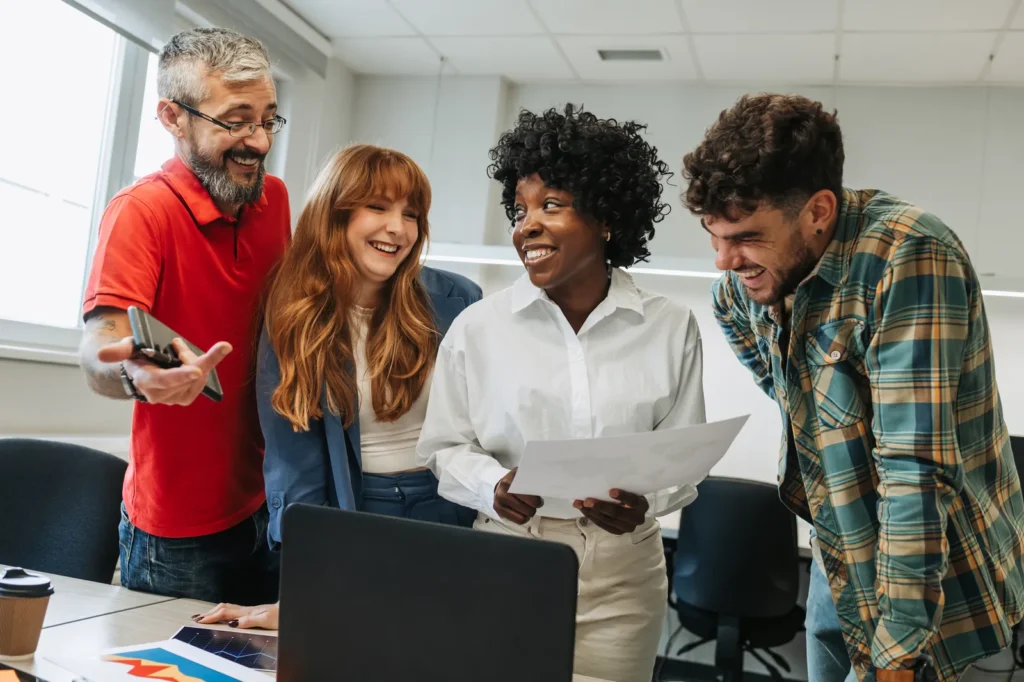 Group of people looking at a laptop screen and smiling